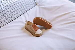 Detailaufnahme von beigen Baby-Segeltuchschuhen mit orangefarbenen Schnürsenkeln