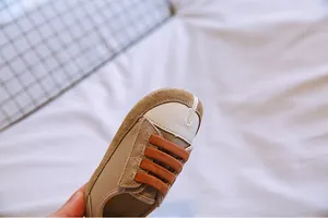 Nahaufnahme des Baby-Canvas-Sneakers mit Split-Toe-Design und orangen Gummizügen