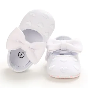 Detailansicht der weißen Babyschuhe mit Herzstickerei und großen weißen Schleifen