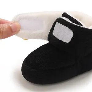 Detalle de bota de invierno para bebé en pana negra con forro de felpa y cierre de velcro.