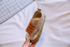 Detailansicht eines khakifarbenen Baby-Segeltuch-Sneakers mit orangefarbenen Bändern.