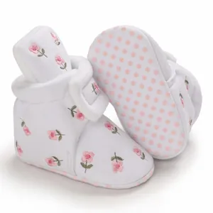 Nahaufnahme weißer Baby-Winterschuhe mit rosa Blumenstickerei und weicher Sohle