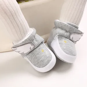 Nahaufnahme graue Babyschuhe mit weißen Engelsflügel-Aufnähern und weichen Sohlen.