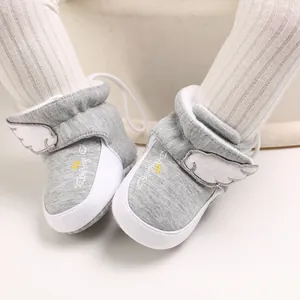 Nahaufnahme von Baby-Winterstiefeln mit Flügeln und Angel-Aufdruck an Babyfüßen.