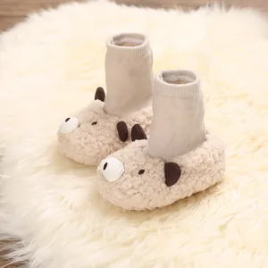 Close-up of beige fuzzy baby cartoon animal booties resting on a soft white faux fur rug.