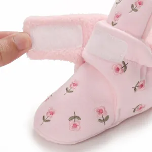 Detail eines rosa Baby-Stiefels mit Blumenmuster, Fleecefutter und Klettverschluss
