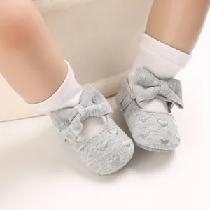Nahaufnahme grauer Baby-Prinzessinnenschuhe mit weißen Herzmustern und großen Schleifen