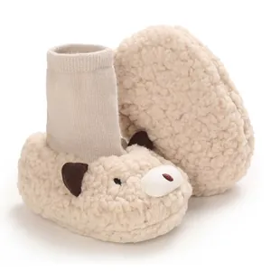 Macro detail of cozy cream fleece baby booties featuring a cute cartoon bear face design