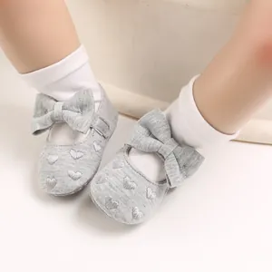 Nahaufnahme graue Baby-Prinzessinenschuhe mit Schleife und Herzstickerei für Mädchen.