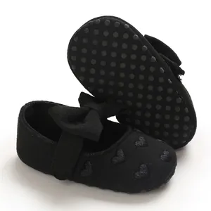 Detailaufnahme schwarzer Baby-Ballerinas mit Herzmuster und rutschfester Gummisohle.