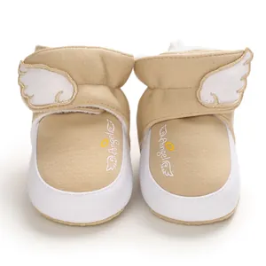 Nahaufnahme khakifarbene Baby Winterschuhe mit weißen Flügeln und Stickereien.