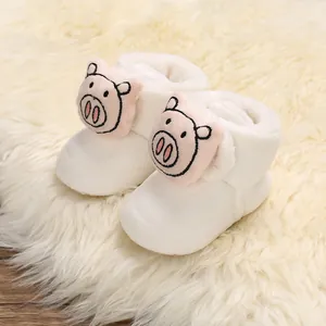 Primer plano de patucos de felpa para bebé con detalle de simpático cerdito rosa