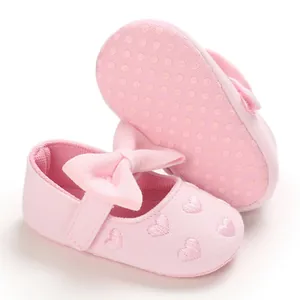 Nahaufnahme rosa Babyschuhe mit bestickten Herzen und einer weichen Stoffschleife