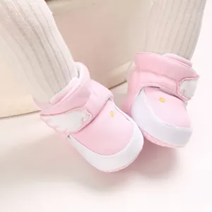 Detaillierte Nahaufnahme von weichen rosa Baby-Winterstiefeln mit Engel-Flügel-Akzenten