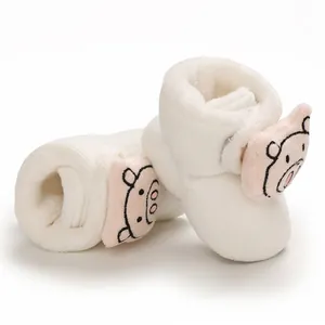 Primer plano de botines de peluche blanco para bebé con un adorable diseño de cerdo rosa
