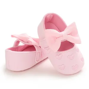 Detail view of pink baby princess shoes with cute bow and embroidered heart pattern