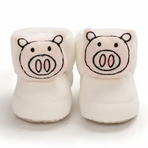 Vista frontal de botines de felpa para bebé con diseño de cerdito de dibujos