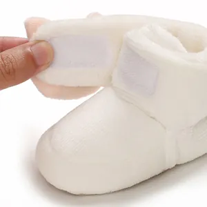 Detalle de zapato de peluche blanco para bebé que muestra el cierre de velcro ajustable