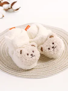 Detaillierte Makroansicht flauschiger weißer Baby-Winterschuhe mit süßem Teddybärengesicht