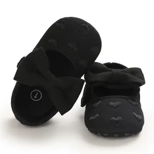 Nahaufnahme von schwarzen Baby-Mary-Janes mit süßem Herzmuster und großer Schleife