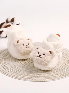Nahaufnahme von weißen, flauschigen Babyschuhen mit süßem Teddybär-Gesicht für den Winter