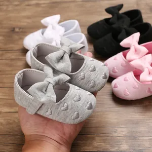 Nahaufnahme von weichen Baby-Prinzessin-Schuhen mit Herzstickerei und einer großen Schleife