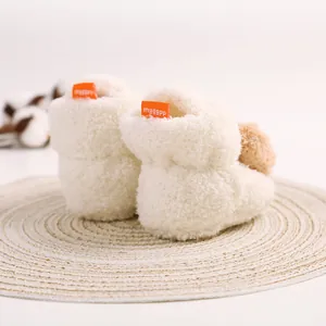 Detailansicht der Rückseite weißer flauschiger Babystiefel mit orangefarbenem Etikett