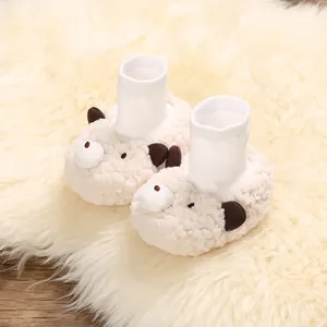 Close-up of fuzzy cream baby booties with cute cartoon bear face and white knit cuffs