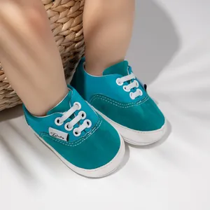 Primer plano de zapatos de bebé color turquesa con cordones blancos y suela de goma.