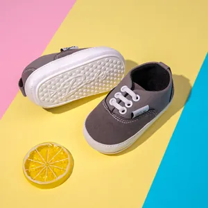 Detalle de zapatos grises para bebé con suelas de goma blancas antideslizantes sobre fondo vivo