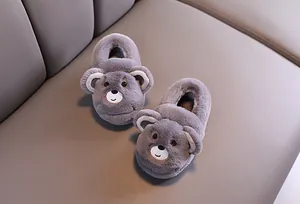 Vue détaillée de chaussons d'hiver en peluche ours gris pour bébés sur surface douce