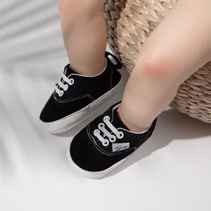 Detalle de zapatos negros para caminar de bebé con suelas de goma blancas y cordones blancos.