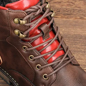 Détail de bottines de travail en cuir marron avec languette rouge et œillets