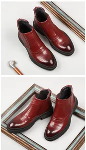 Detailed view of burgundy leather Chelsea boots with elegant brogue perforations.