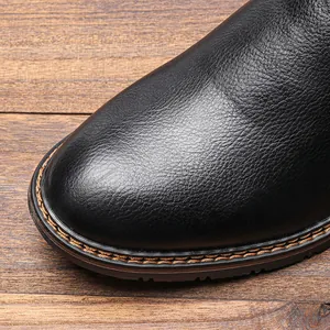 Vista detallada de la puntera de cuero negro y las costuras de una bota para hombre.
