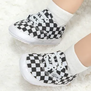Primer plano de zapatos clásicos de bebé a cuadros blancos y negros en alfombra.