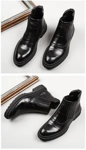 Detail view of men's black leather Chelsea boots with brogue carving and thick soles