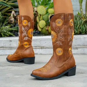 Detalle de botas vaqueras marrones con bordado de girasol vibrante y tacón ancho cómodo.