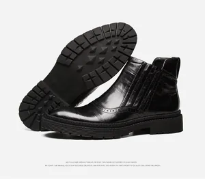 Men's black leather Chelsea boots featuring wingtip brogue detail and thick rubber sole
