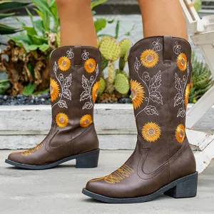 Vista detallada de botas occidentales marrones con bordado de girasol en una modelo