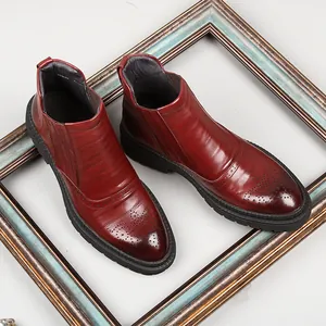 Men's burgundy leather Chelsea boots featuring elegant brogue carving and thick soles.