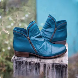 Detailed side view of teal leather ankle boots with vintage pleats and side zipper