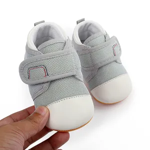 Detail of grey mesh baby walking shoes with white toe cap and anti-slip rubber sole.