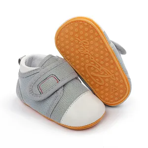 Close-up of grey breathable mesh baby walking shoes with non-slip orange rubber soles.