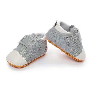Detail view of breathable grey mesh baby shoes with non-slip orange rubber soles.