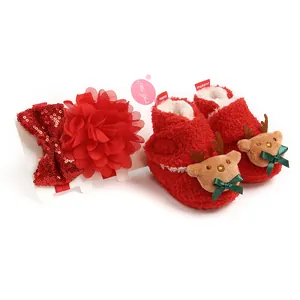 Nahaufnahme der roten, flauschigen Weihnachts-Babyschuhe mit Rentier und Pailletten-Stirnband