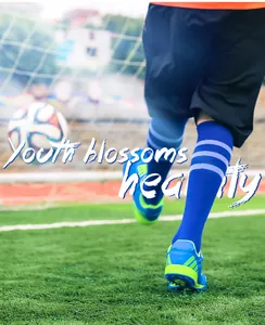 Detailed view of children's blue turf soccer shoes in action on a lush green field.