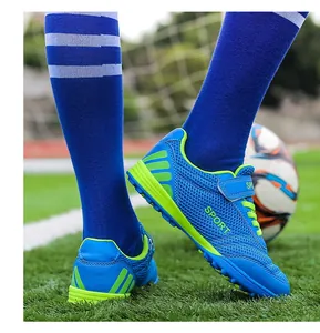 Close-up of blue and green mesh children's soccer shoes with velcro strap on grass.