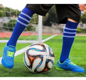 Detailed view of kids breathable blue soccer shoes with turf studs on a green field