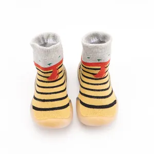 Front view of striped baby sock shoes featuring thick tan rubber soles for first walkers